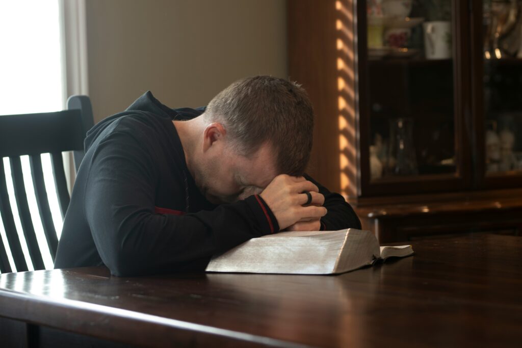 ansiedade-oracao-biblia Pessoa orando com a Bíblia aberta buscando paz em meio à ansiedade