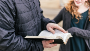 Pessoa mostrando a Bíblia e compartilhando o evangelho em conversa pessoal